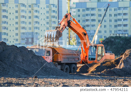 Excavator loads the earth into a dump truck. 47954211