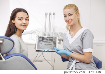 Dentist and patient choosing treatment in a consultation with medical equipment in the background Dentist and patient choosing treatment in a consultation with medical equipment in the background 47954483
