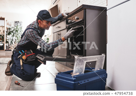 Don't delay with repair. Close-up of repairman examining oven 47954738