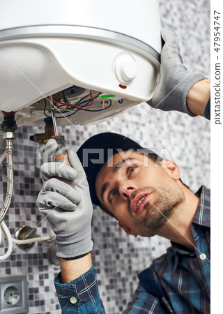 Set up boiler. Worker set up electric heating boiler at home bathroom 47954747