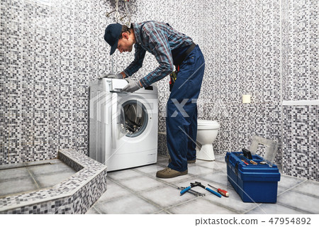 Checking washing machine work. Working man plumber in bathroom Checking washing machine work. Working man plumber in bathroom 47954892