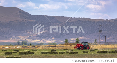 Red tractor on a field near the base of a mountain Red tractor on a field near the base of a mountain 47955031