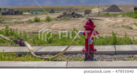 Red fire hydrant with connected hose and wrench Red fire hydrant with connected hose and wrench 47955040