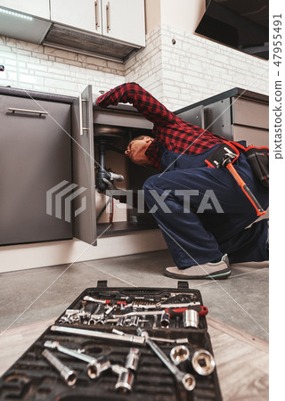 All tools just in case. Seniour handyman repairing washbasin at the kitchen 47955491