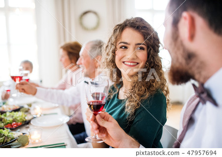 A young couple sitting at a table on a indoor birthday party, clinking glasses. 47957694
