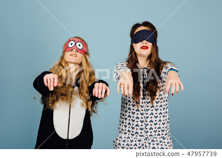 two cheerful girls in masks for sleeping have fun playing sleepwalking two cheerful girls in masks for sleeping have fun playing sleepwalking 47957739