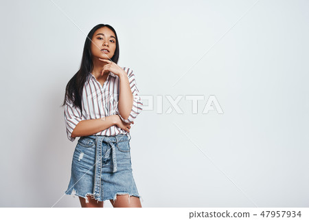 Elegance and beauty. Young asian woman in striped shirt with hand on chin looking at camera while 47957934
