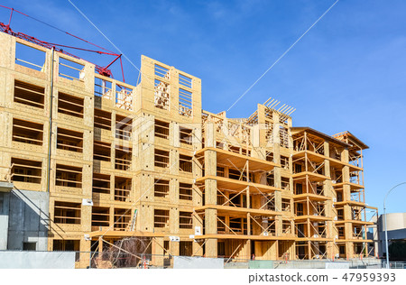 Residential apartment building with red crane above it on blue sky background Residential apartment building with red crane above it on blue sky background 47959393