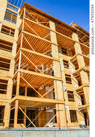 Six storey frame building under construction on concrete foundation bed. Six storey frame building under construction on concrete foundation bed. 47959394