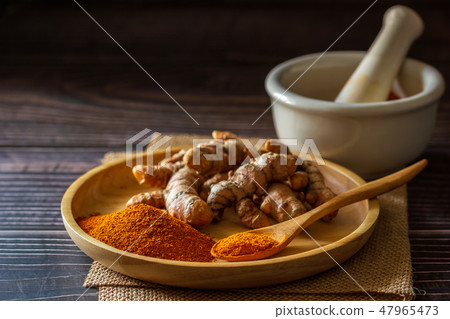 Turmeric powder on dish with mortar and pestle. Turmeric powder on dish with mortar and pestle. 47965473