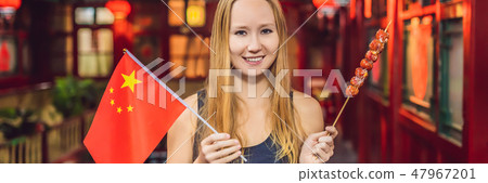 Enjoying vacation in China. Happy woman tourist with a Chinese flag and with traditional Chinese 47967201