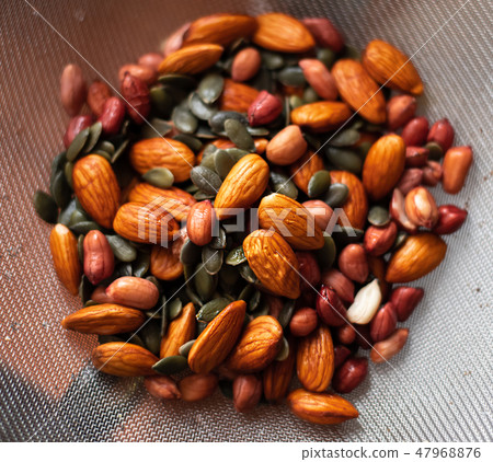 A mixture of wet washed nuts and seeds on the sieve. Peanuts, pumpkin seeds, almonds A mixture of wet washed nuts and seeds on the sieve. Peanuts, pumpkin seeds, almonds 47968876