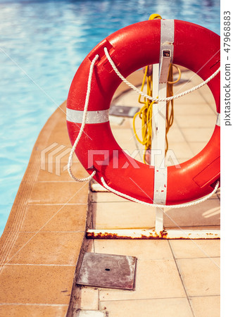 Lifebuoy life ring with rope attached to the post next to the pool in city in tropical country 47968883