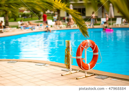 Lifebuoy life ring with rope attached to the post next to the pool in city in tropical country Lifebuoy life ring with rope attached to the post next to the pool in city in tropical country 47968884