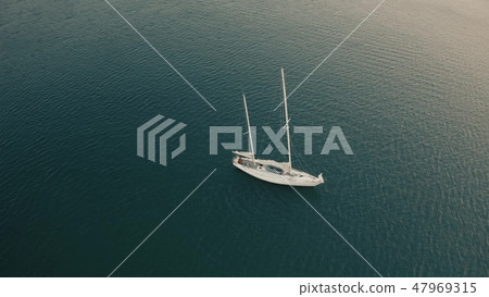 Aerial view of unknown man cruising on his sailboat with removed sails Aerial view of unknown man cruising on his sailboat with removed sails 47969315