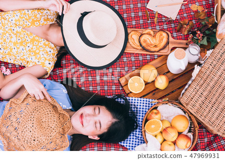 female friends enjoying picnic together in a park. female friends enjoying picnic together in a park. 47969931