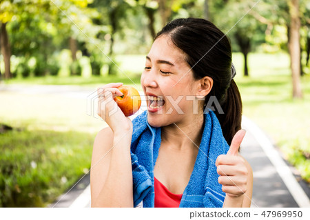 Happy woman is holding apple in the park 47969950