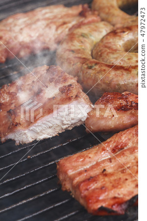 Grilled sausage and pork cooking on flaming grill. Grilled sausage and pork cooking on flaming grill. 47972473