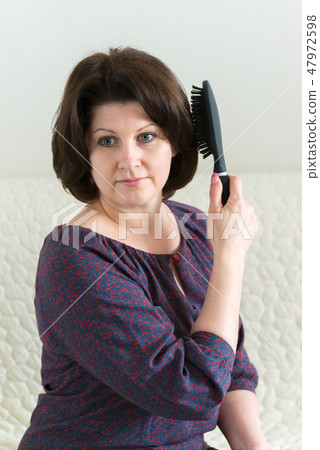 woman with a massage comb brushes her hair 47972598