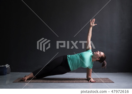 young woman practices yoga asana Vasishthasana or side plank pose 47972616