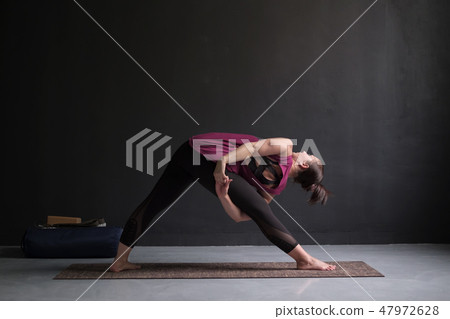 Girl standing in Utthita Trikonasana, extended triangle pose. Girl standing in Utthita Trikonasana, extended triangle pose. 47972628