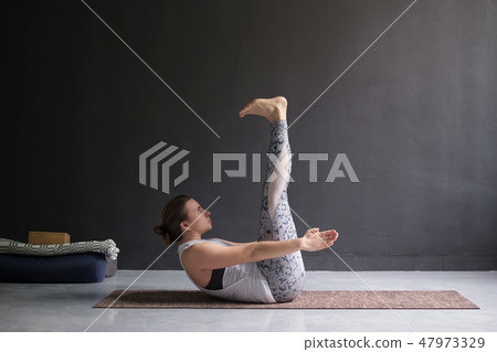 Young woman practicing yoga asana Ardha Navasana 47973329