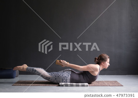 Woman practicing yoga, stretching in Salabhasana exercise, Double Leg Kicks pose Woman practicing yoga, stretching in Salabhasana exercise, Double Leg Kicks pose 47973391