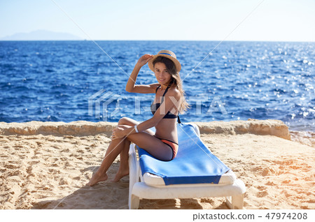 Beautiful woman sunbathing on a beach at tropical travel resort, enjoying summer holidays. Young Beautiful woman sunbathing on a beach at tropical travel resort, enjoying summer holidays. Young 47974208