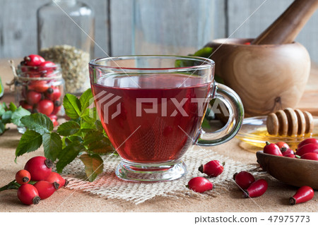 A cup of rose hip tea with fresh rose hips 47975773