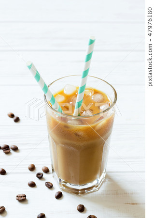 Coffee with ice, milk and striped straws in glass 47976180