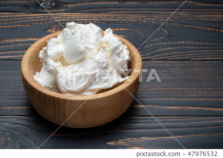 Traditional Mascarpone cheese in wooden bowl on table Traditional Mascarpone cheese in wooden bowl on table 47976532