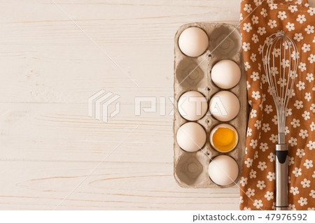 Metal whisk on towel and raw white chicken eggs 47976592