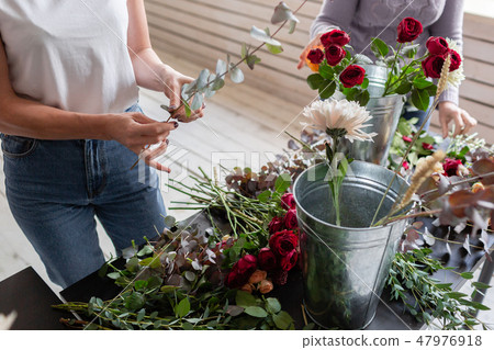 Close-up flowers in hand. Florist workplace. Woman arranging a bouquet with roses, chrysanthemum Close-up flowers in hand. Florist workplace. Woman arranging a bouquet with roses, chrysanthemum 47976918