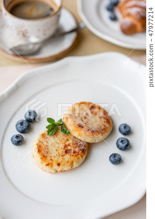 Cheesecake, fresh blueberry and cappuccino. Cottage cheese pancakes or curd fritters on white plate 47977214