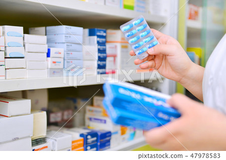 Pharmacist holding medicine box and capsule pack  47978583