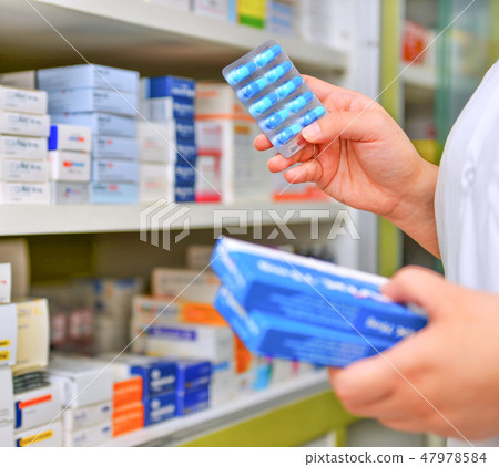 Pharmacist holding medicine box and capsule pack  47978584