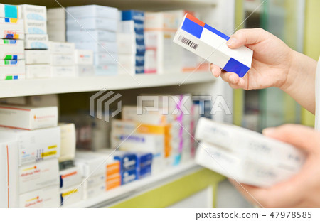 Pharmacist holding medicine box in pharmacy 47978585