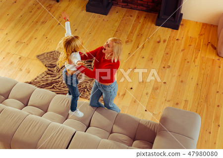 Positive delighted blonde female playing with her daughter 47980080