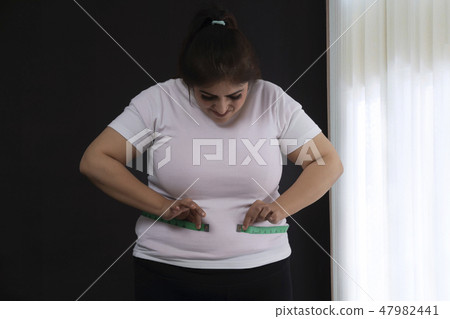 woman measuring her waist with a tape measure 47982441