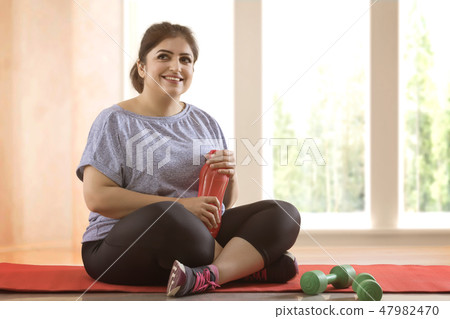 Overweight woman taking a break from exercising Overweight woman taking a break from exercising 47982470