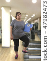 fat woman in a gym holding a weight scale 47982473