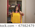 woman trying to wear small size of yellow t-shirt 47982479