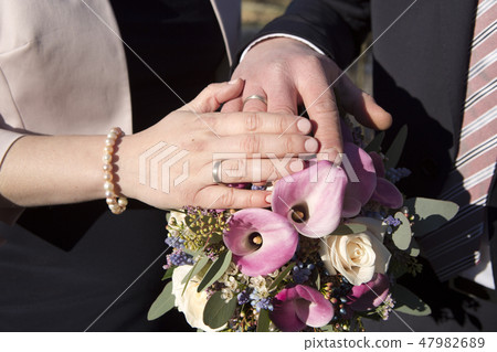Hands of bride and groom with flower bouquet 47982689