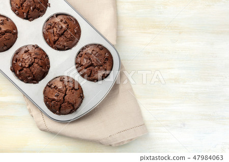 An overhead photo of chocolate muffins in a pan, shot from the top on a light background with copy 47984063