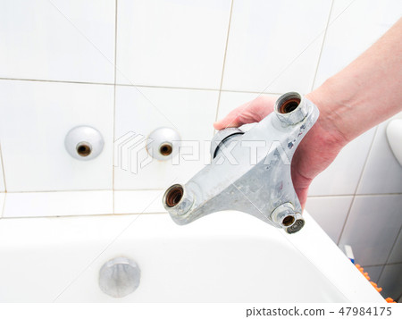 Plumber holding a dual outlet shower faucet 47984175