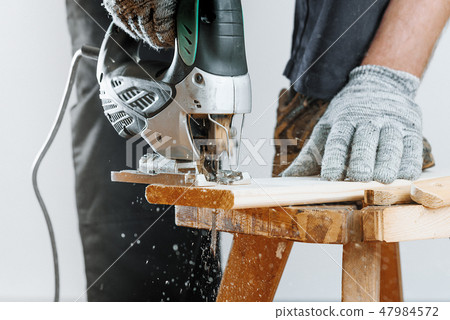 Crop man jigsaw saws Board and flying sawdust. Woodwork Concept 47984572