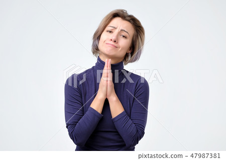 Woman holding palms pressed together in front of her, asking for forgiveness 47987381