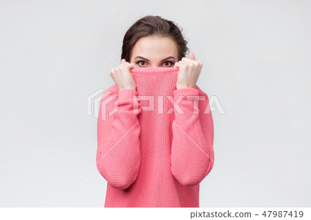 Girl pulling her trendy sweater over head hdidng from problems. 47987419