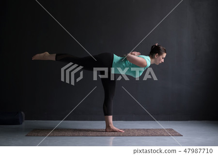 Sporty fit woman practices yoga asana Virabhadrasana 3 47987710