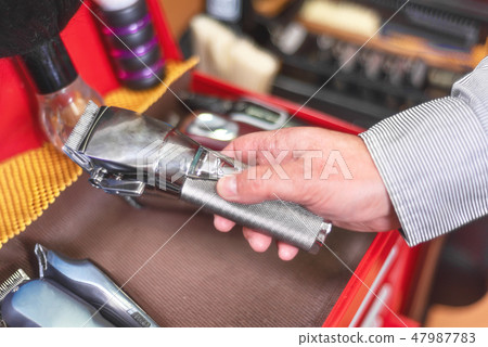Close up of barber hand picking hair clipper at barber shop. 47987783
